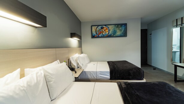 Habitación de hotel con dos camas, un cuadro en la pared y un escritorio con una lámpara.
