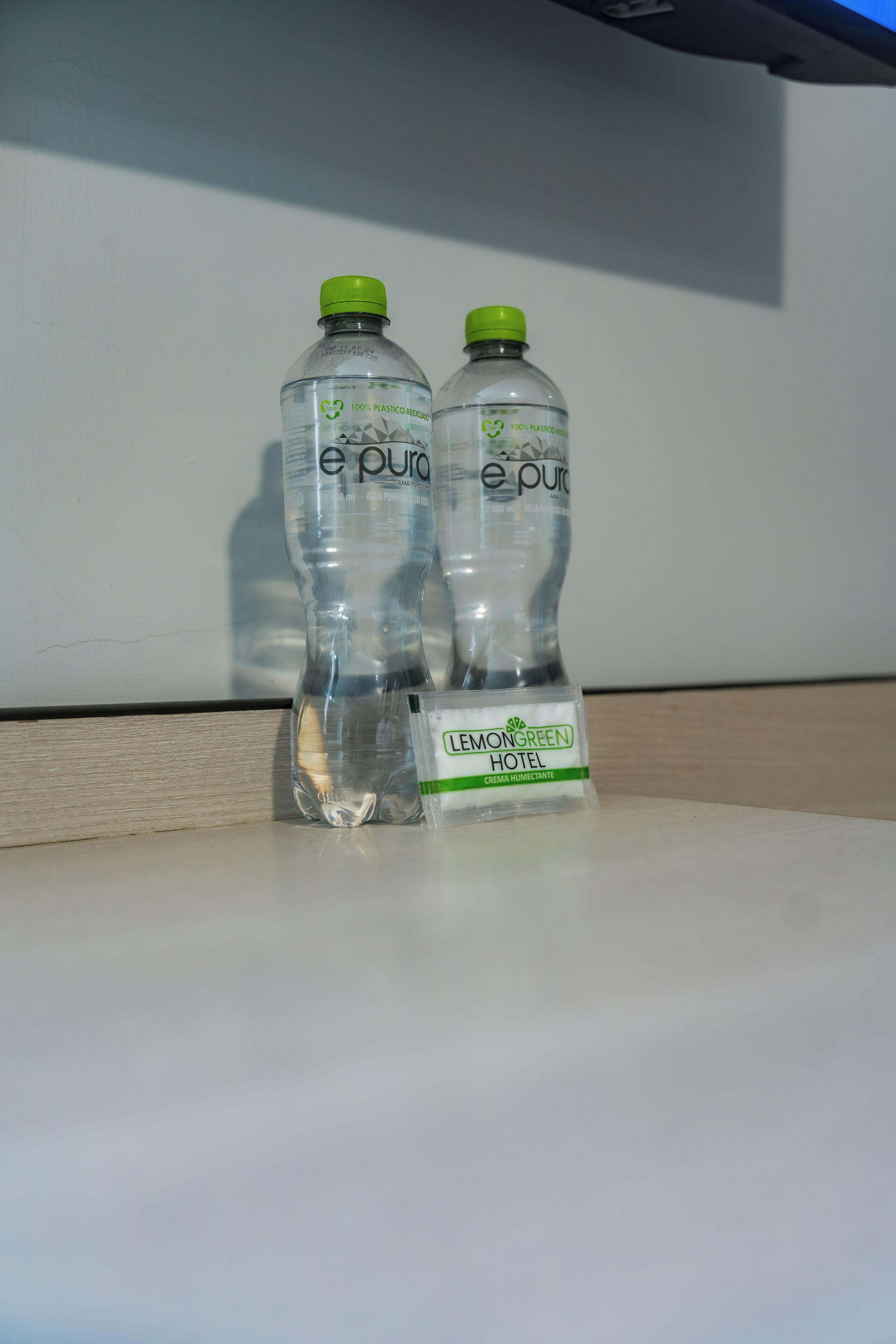 Two bottles of e-pura water and a small item with the Lemongreen Hotel logo.