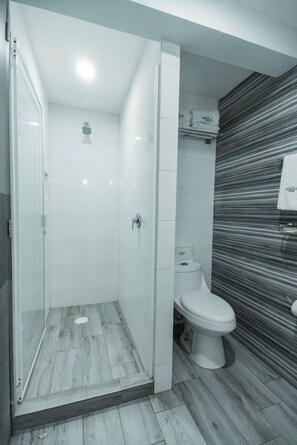 Un baño moderno con cabina de ducha de vidrio, inodoro y pared a rayas.