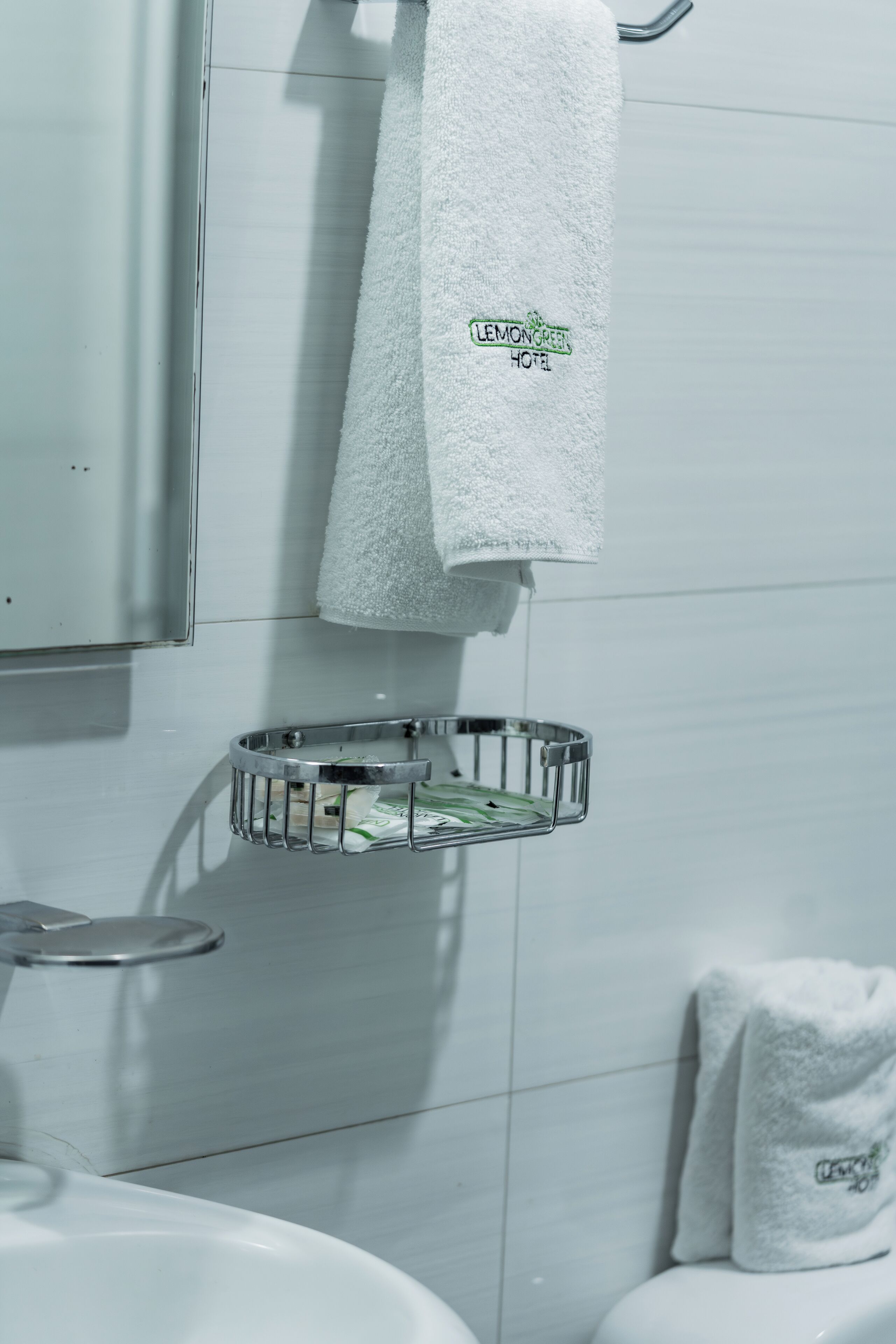 Un baño con un lavabo blanco, un perchero con una toalla y otro perchero de metal con una toalla.