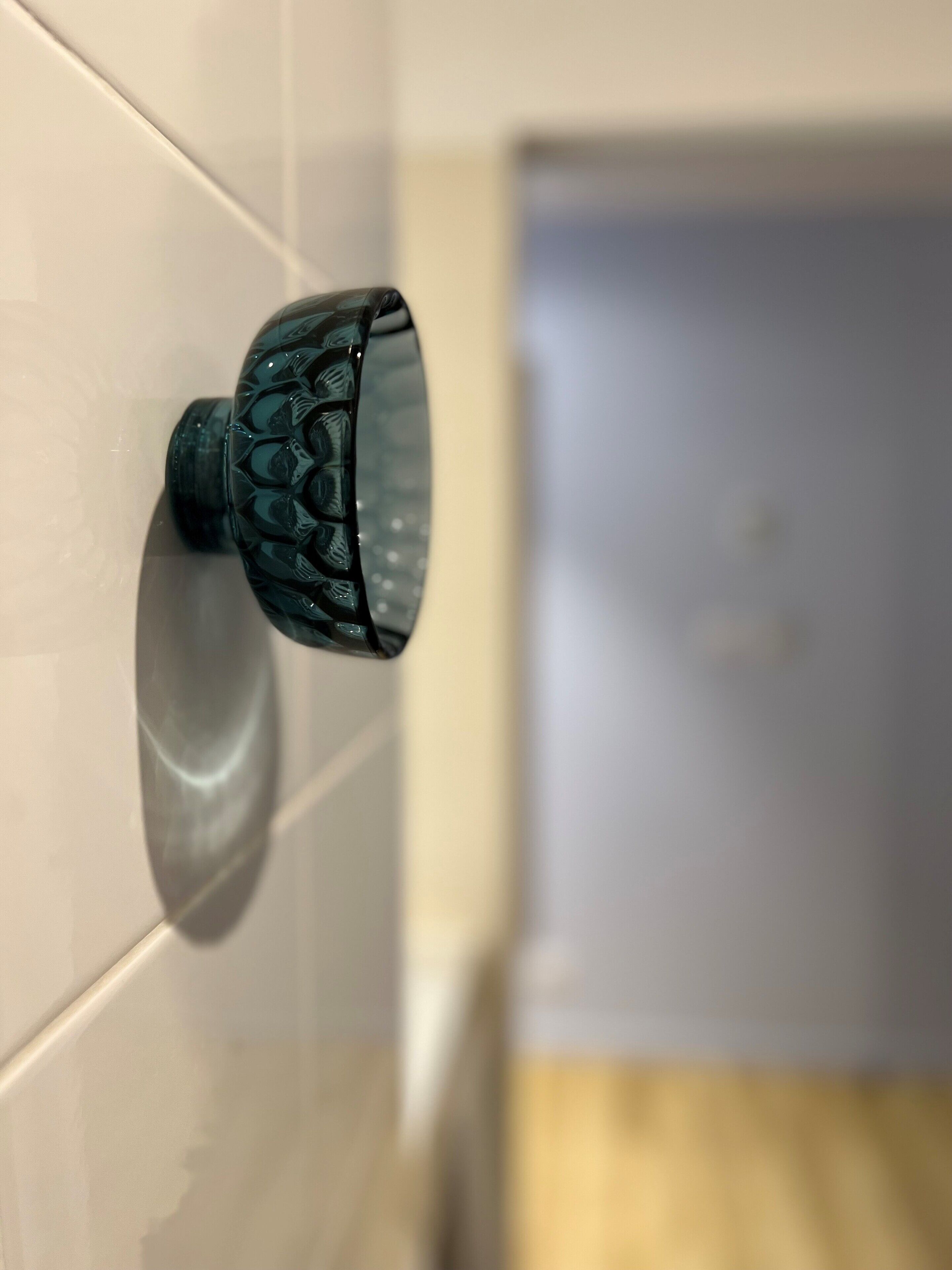 A bathroom with a white tiled wall and a green, textured door handle.