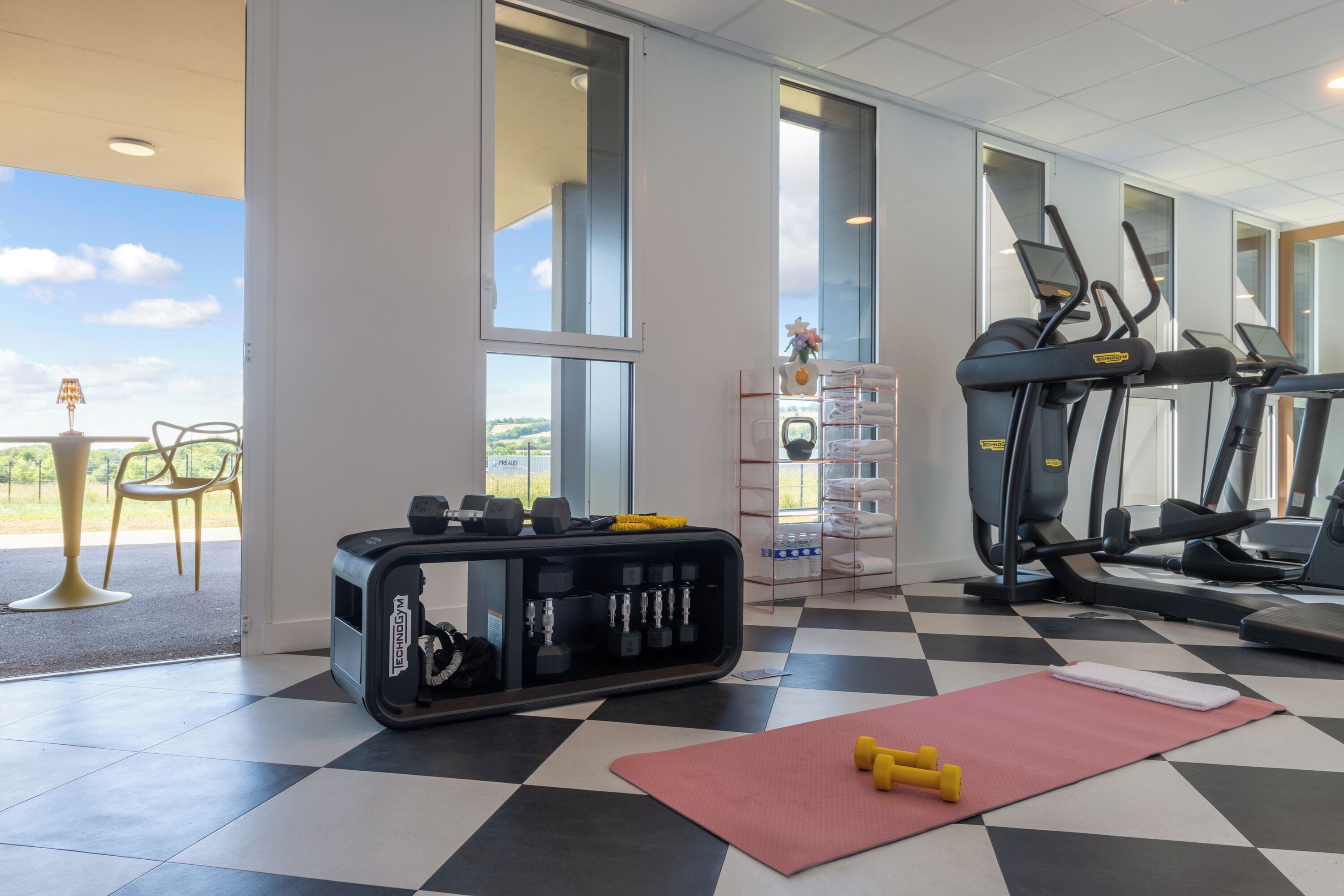 A gym with treadmills, dumbbells, and a yoga mat.