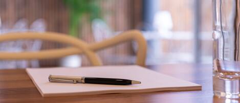A wooden table with a notebook, a pen, and a glass of water.