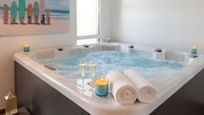 Un bain à remous avec des bougies, deux coupes de champagne et des serviettes enroulées.
