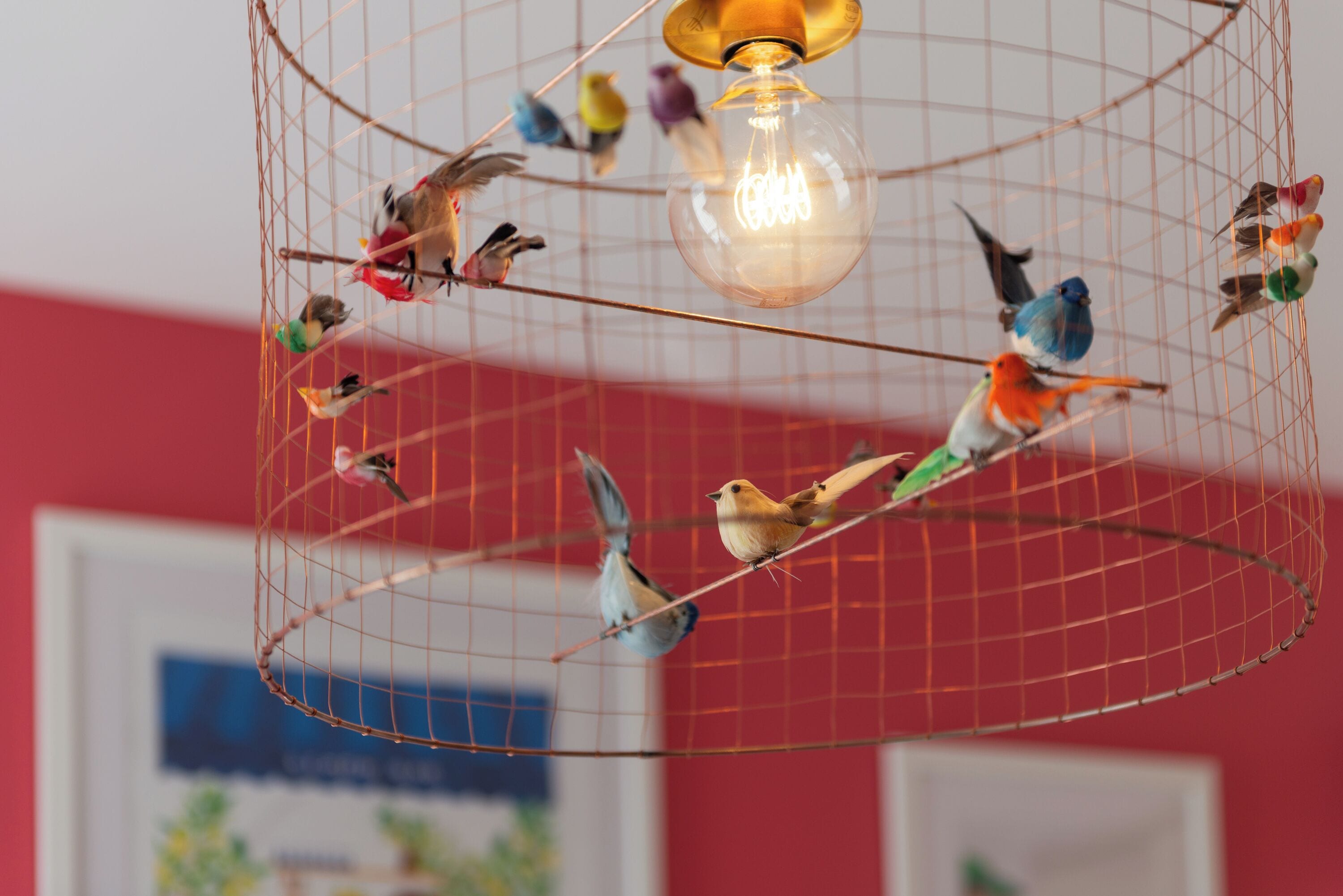 A birdcage with multiple birds and a light fixture.