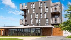 Un hôtel moderne doté de nombreux balcons, de grandes fenêtres et d’une façade en bois.