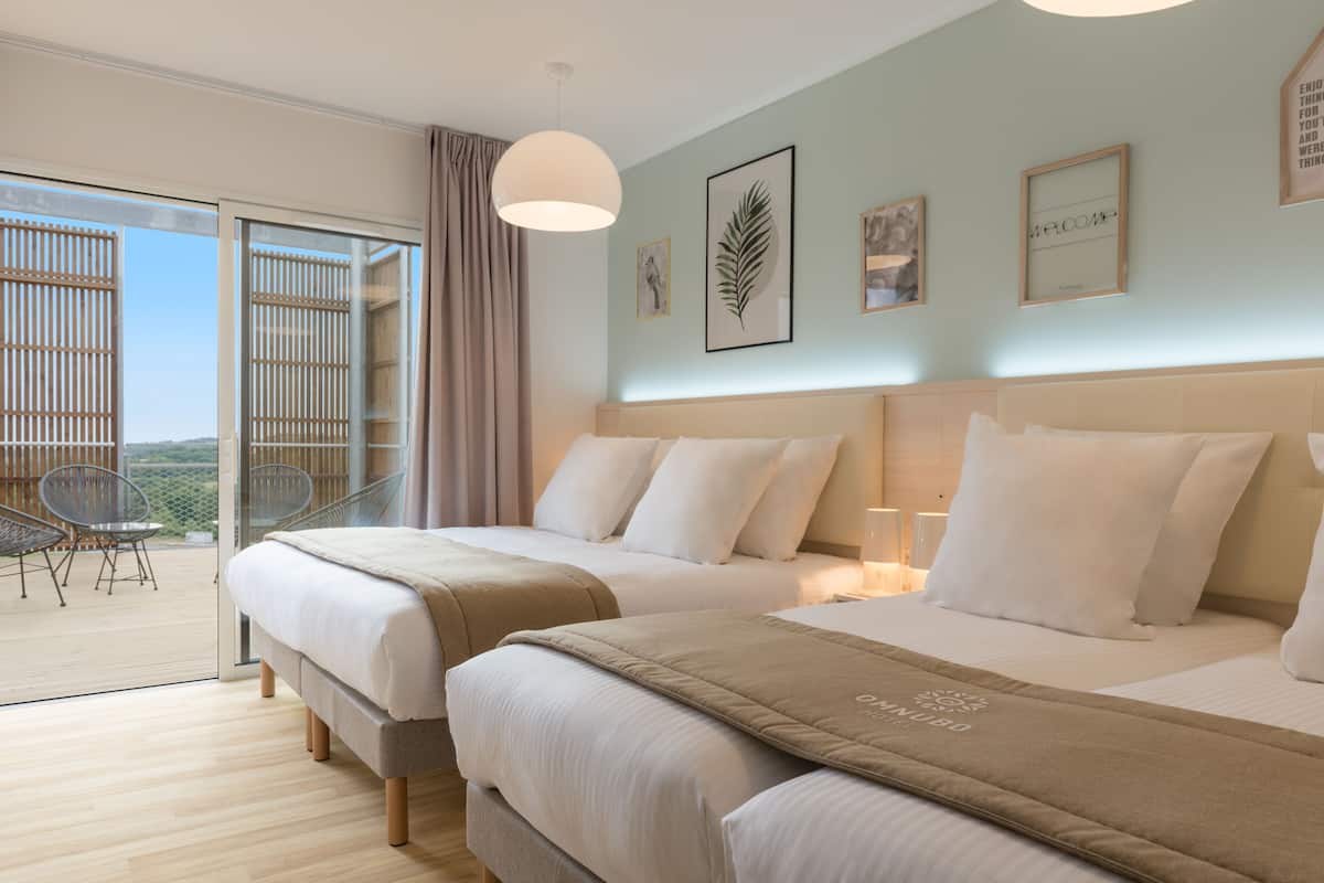Een hotelkamer met twee bedden, een balkon en een mooi uitzicht, plus een groot raam.
