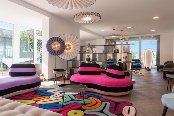 Un salón moderno con sofás coloridos, un tapete estampado y un espacio luminoso con ventanas amplias y lámparas de diseño contemporáneo.