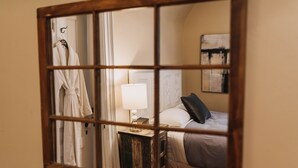 Een hotelkamer met een bed, een nachtkastje met een lamp, een badjas aan een haak en een schilderij aan de muur.