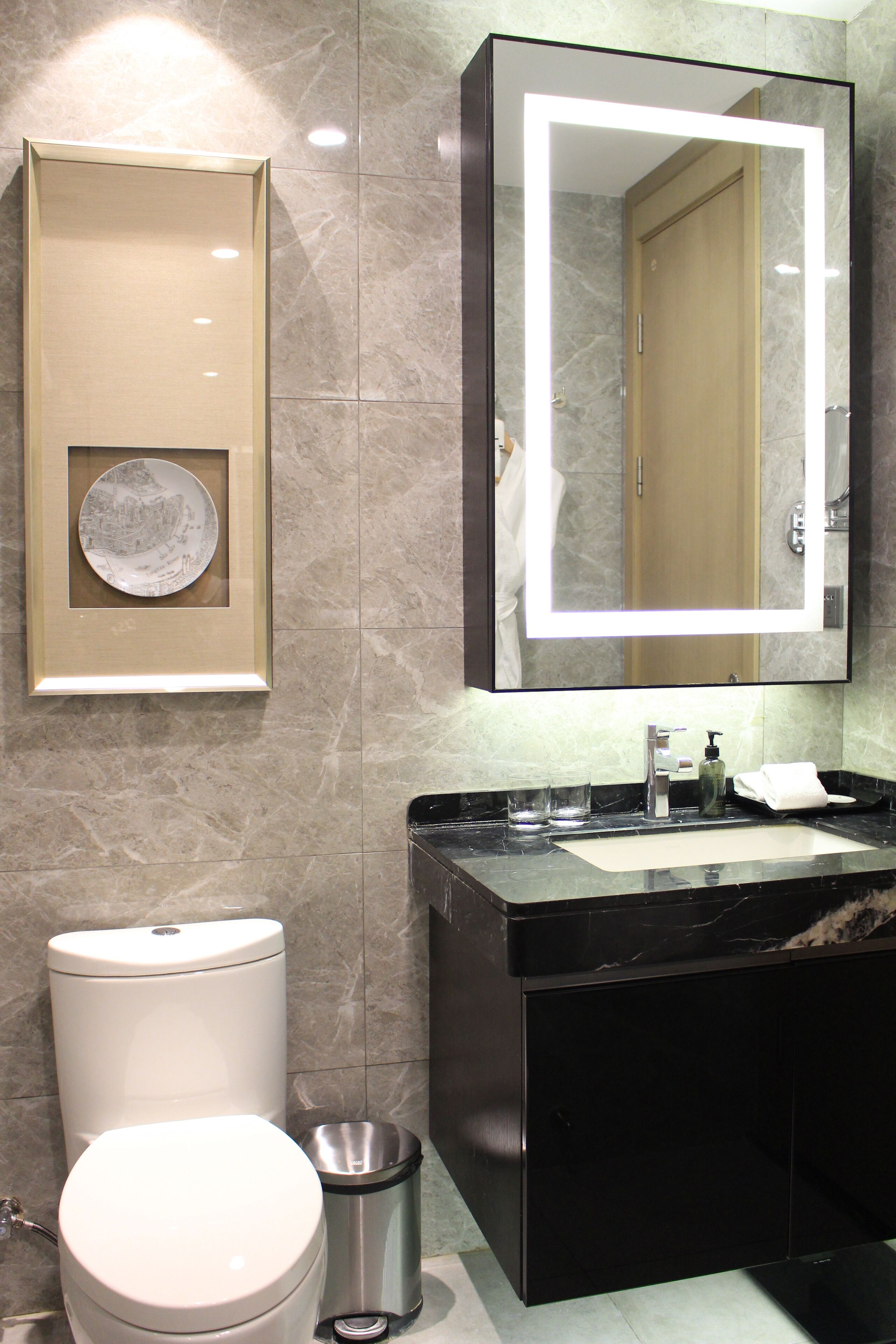 A bathroom with a toilet, sink, and mirror.