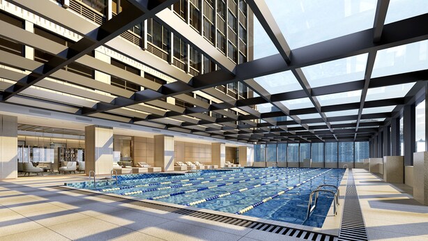 A modern indoor swimming pool with a glass ceiling, lounge area, and seating.