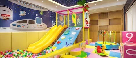 Un área de juegos infantiles con un tobogán, piscina de bolas y diversas estructuras recreativas.