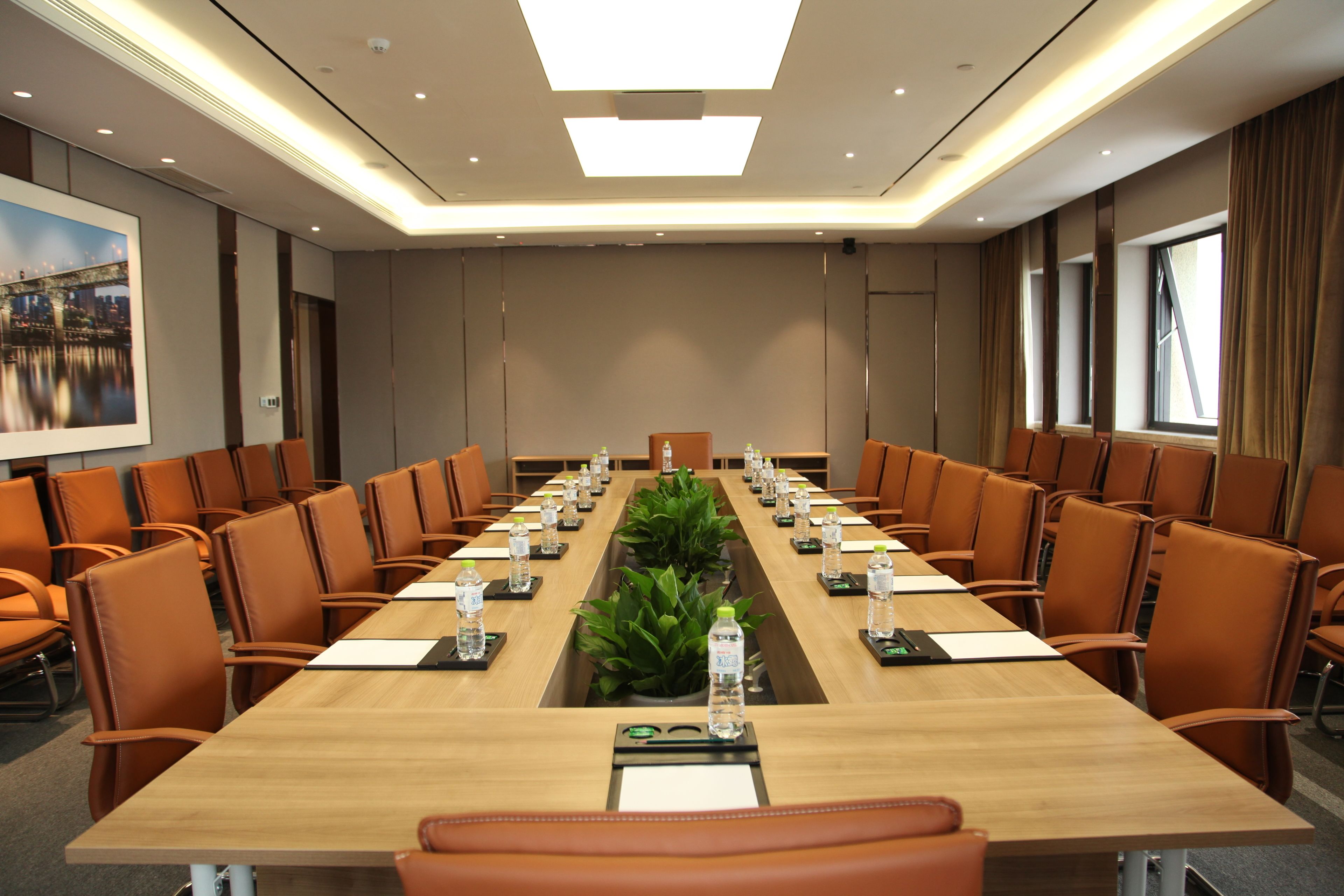 A conference room with a long table, chairs, water bottles, and a plant.