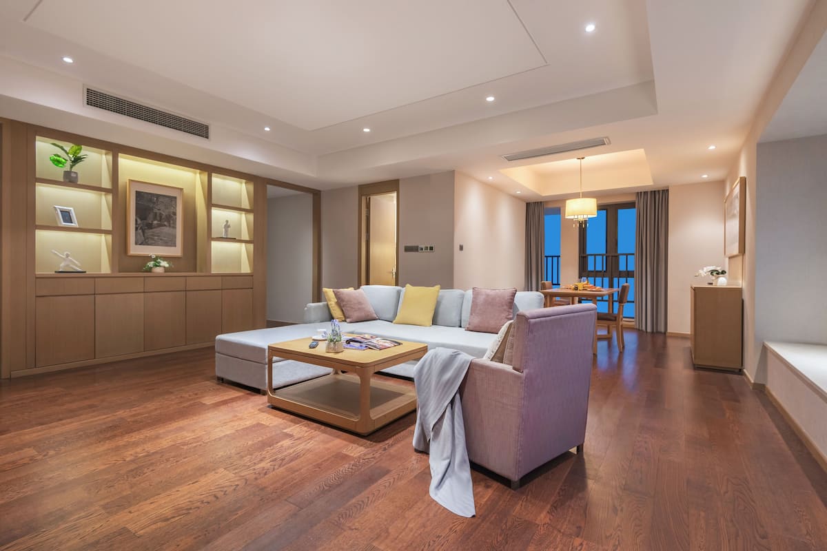 A modern living room with a sofa, armchair, coffee table, and a dining area with a table and chairs.