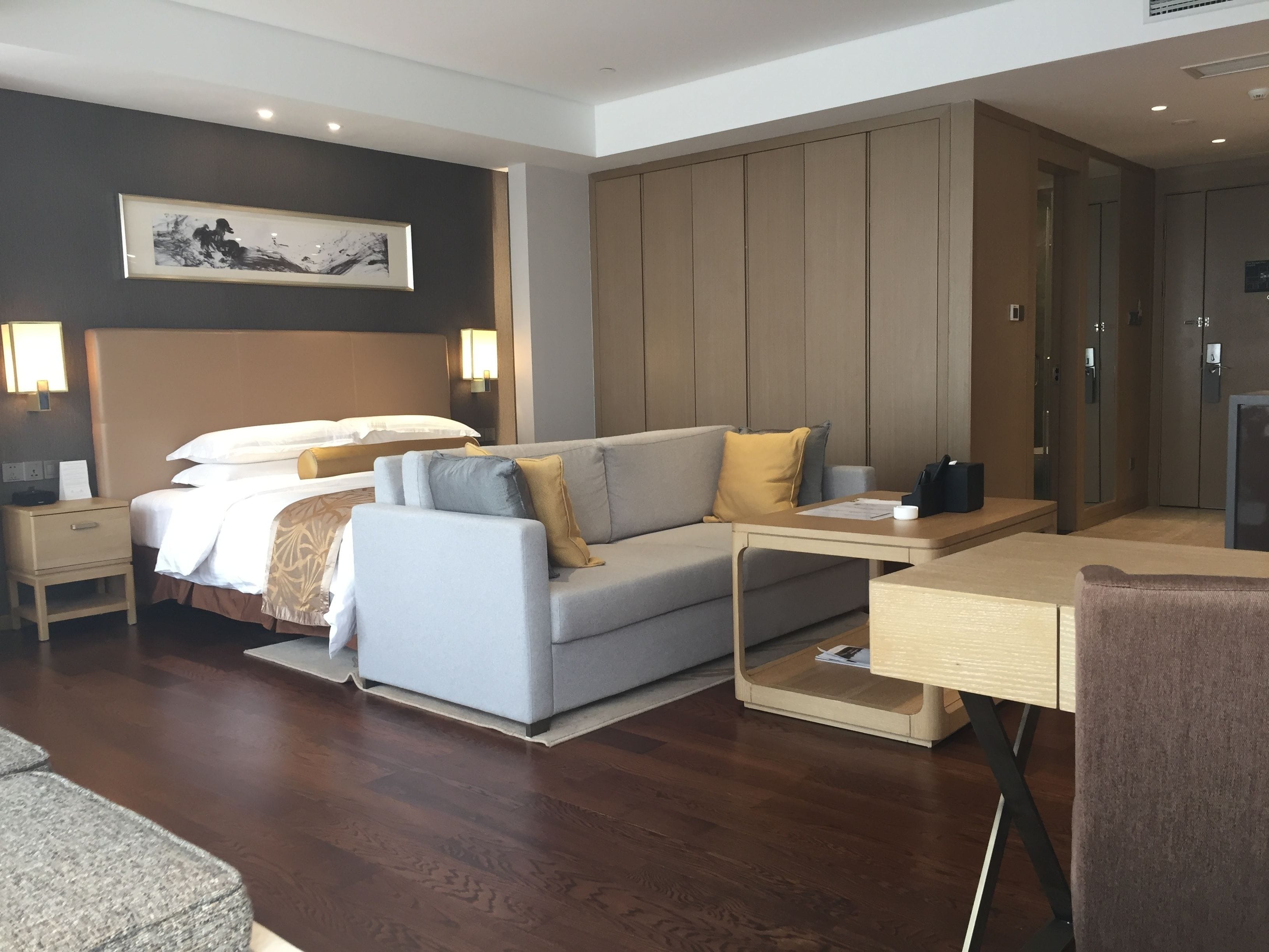Une chambre d’hôtel moderne équipée d’un lit, d’un canapé, d’un bureau et d’une armoire.