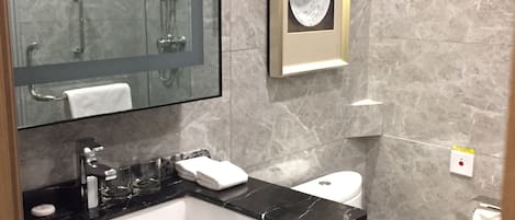 A modern bathroom with a glass-enclosed shower, a white toilet, and a black marble sink.