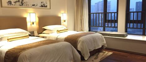 Habitación de hotel con dos camas, un ventanal con vistas a edificios y un cuadro en la pared.