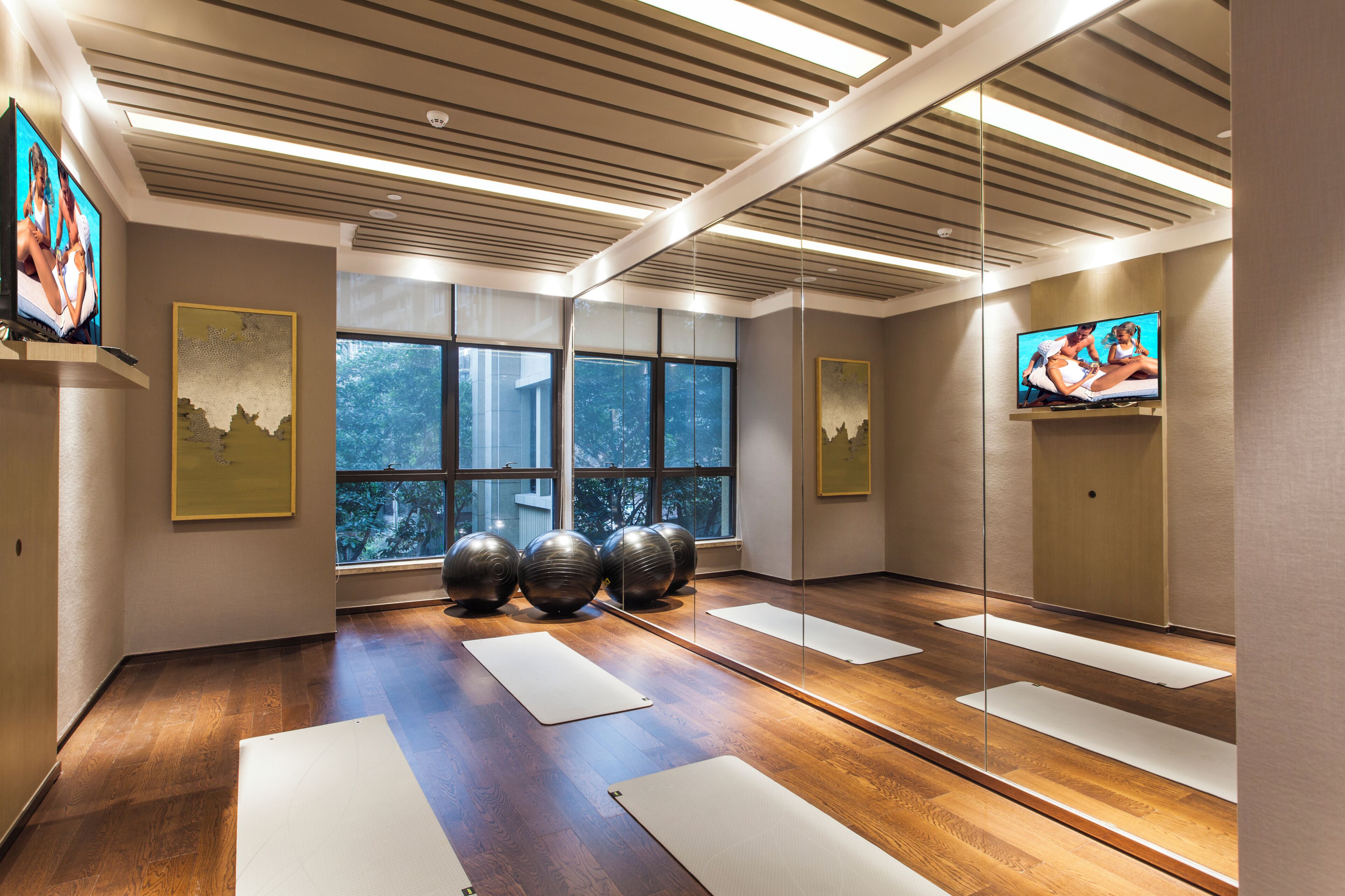 Une pièce spacieuse dotée de grandes fenêtres, de ballons d’exercice et de tapis de yoga.