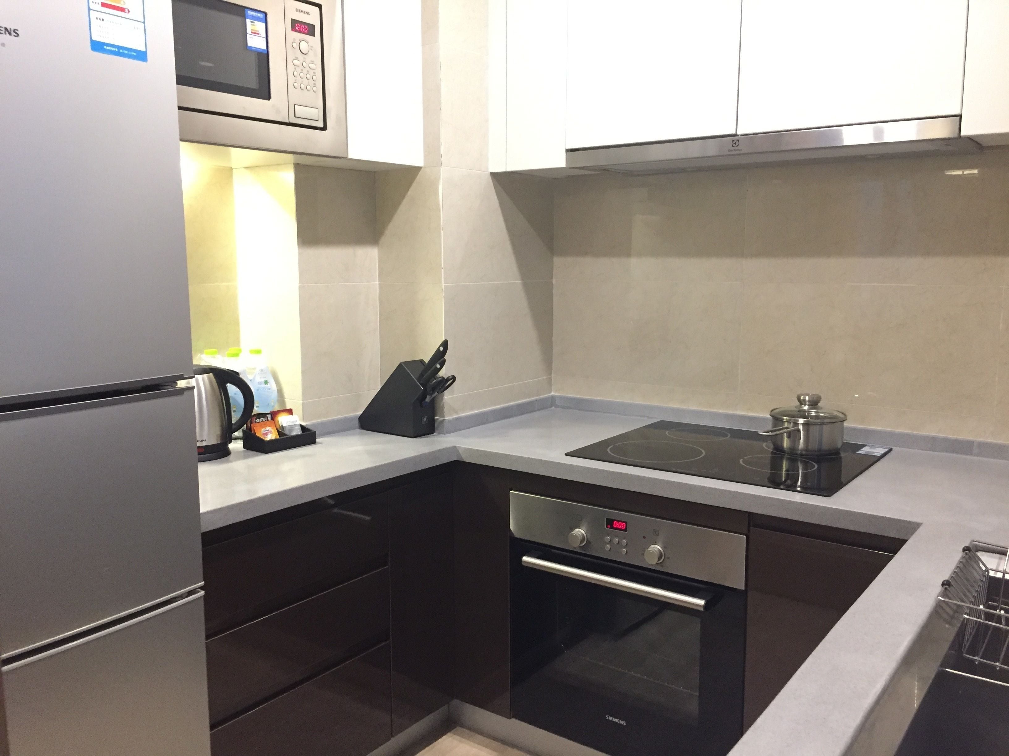 A modern kitchen with a built-in oven, microwave, and a kettle on the counter.