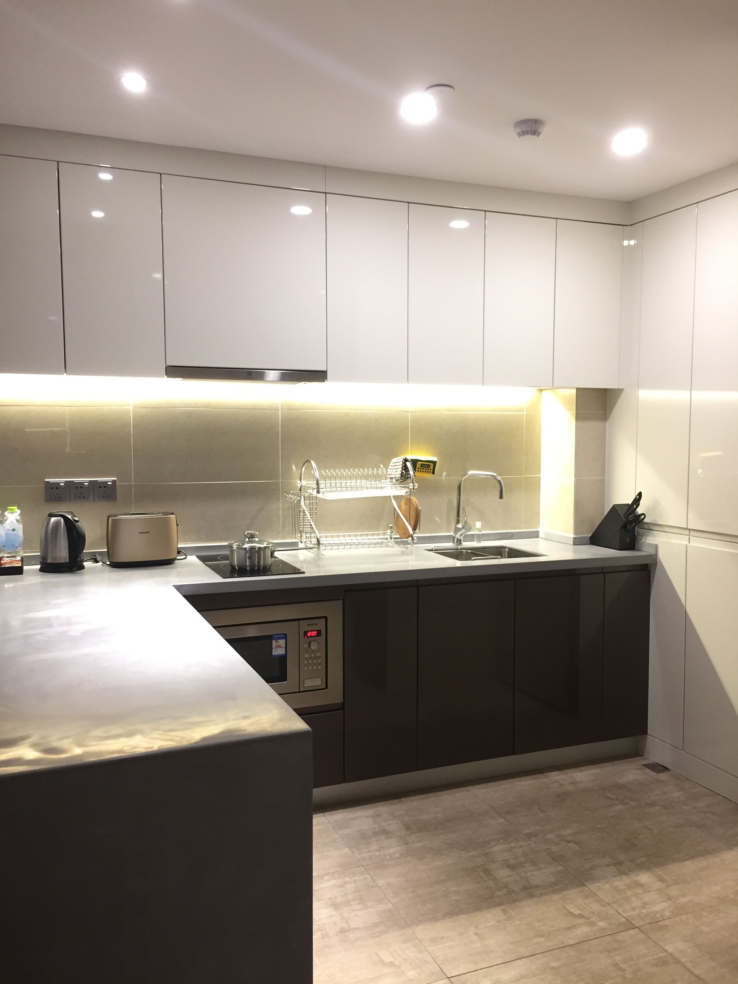 A modern kitchen with white cabinets, a stainless steel sink, and a built-in oven.