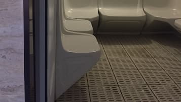 A restroom with three toilets, a control panel, and a tiled floor.