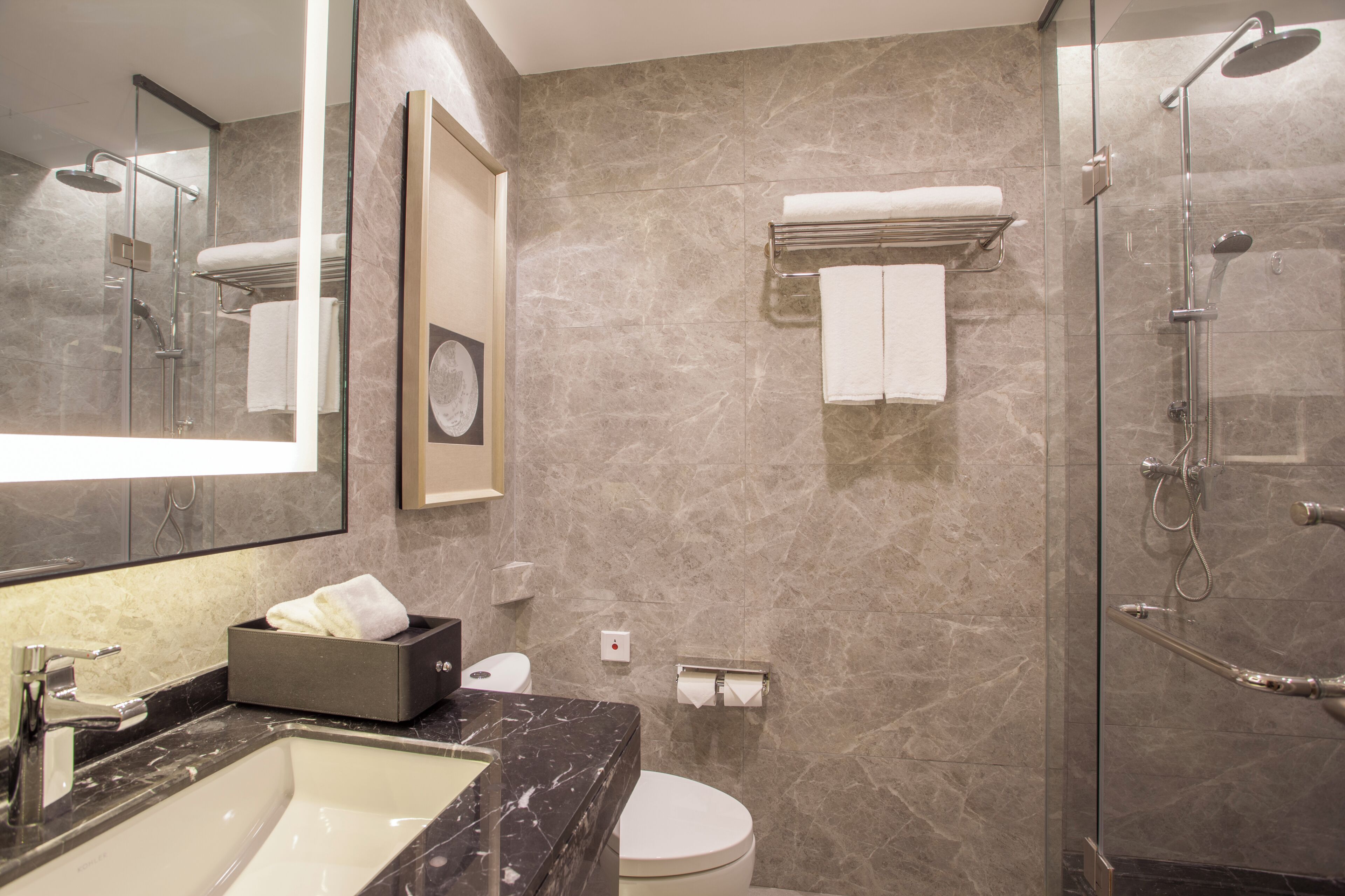 Ein modernes Badezimmer mit Marmorwaschbecken, Toilette, einer Duschkabine und einem Handtuchhalter.