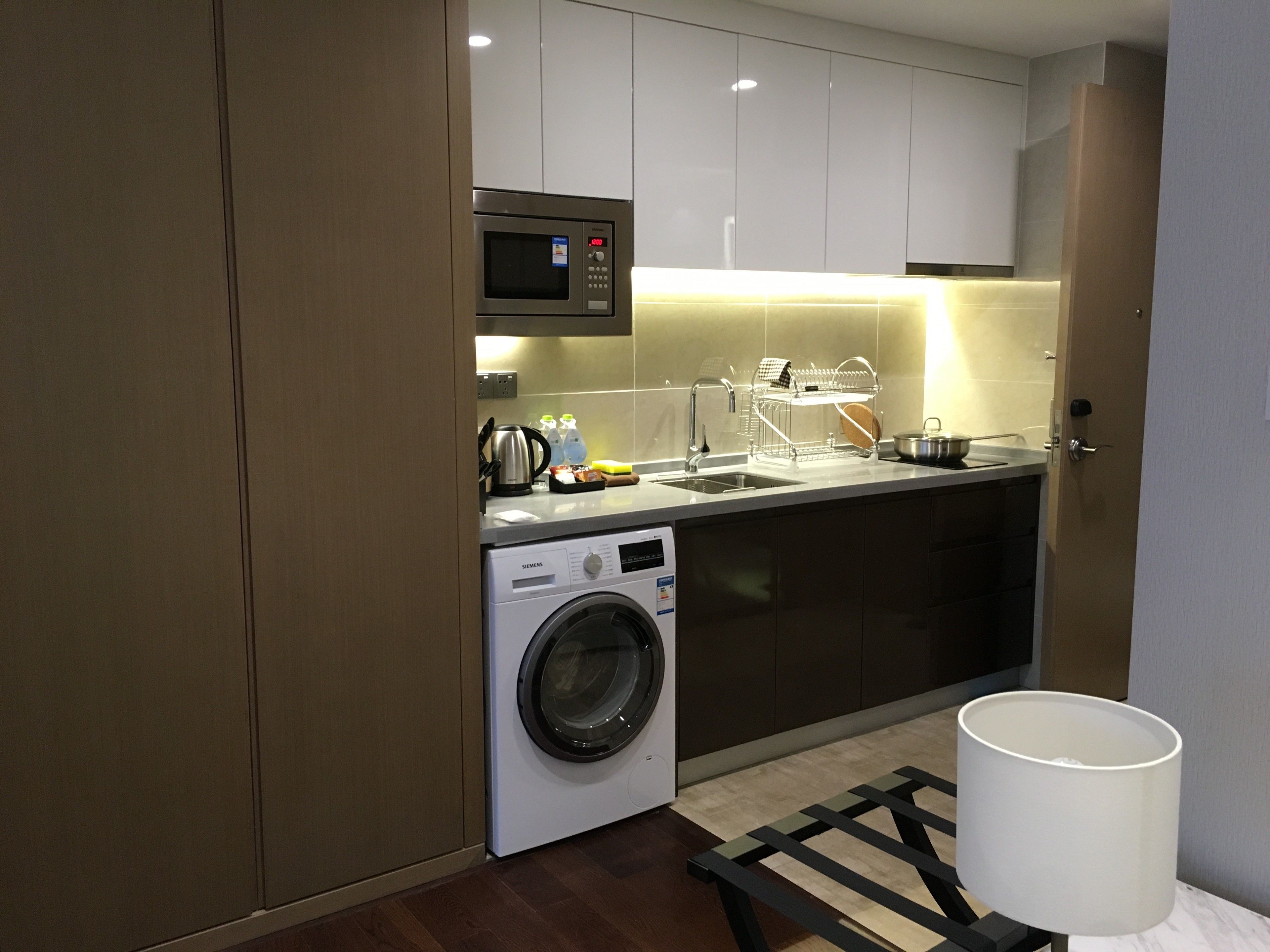A compact kitchen with a washing machine, microwave, and a sink.