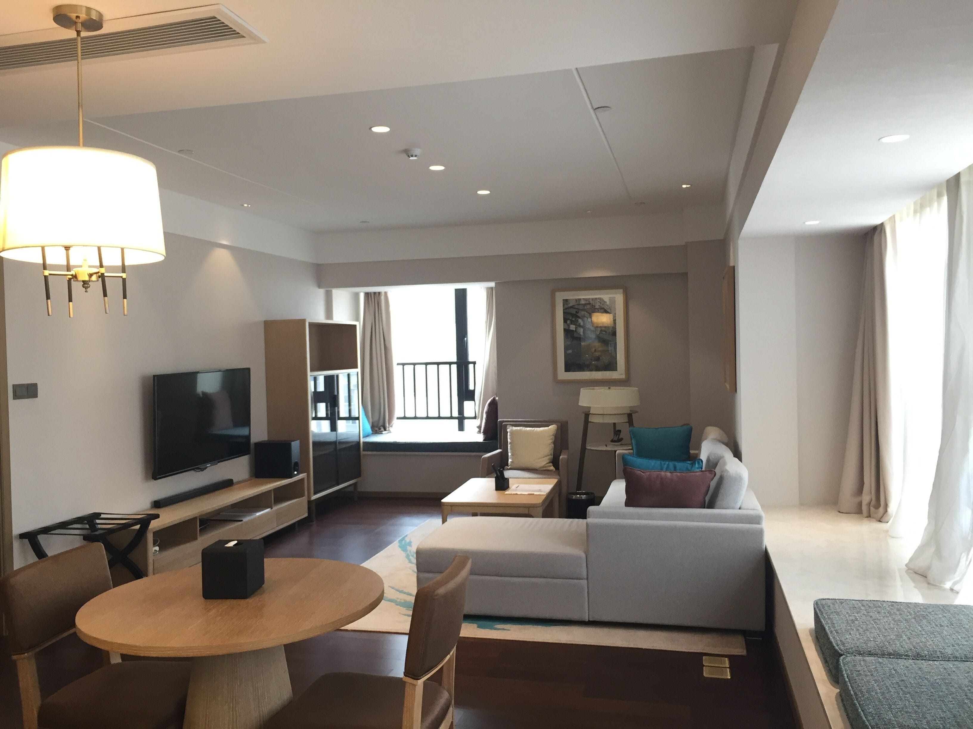 Une chambre d’hôtel moderne dotée d’une télévision à écran plat, d’une table à manger en bois, d’un canapé et d’un balcon avec vue.