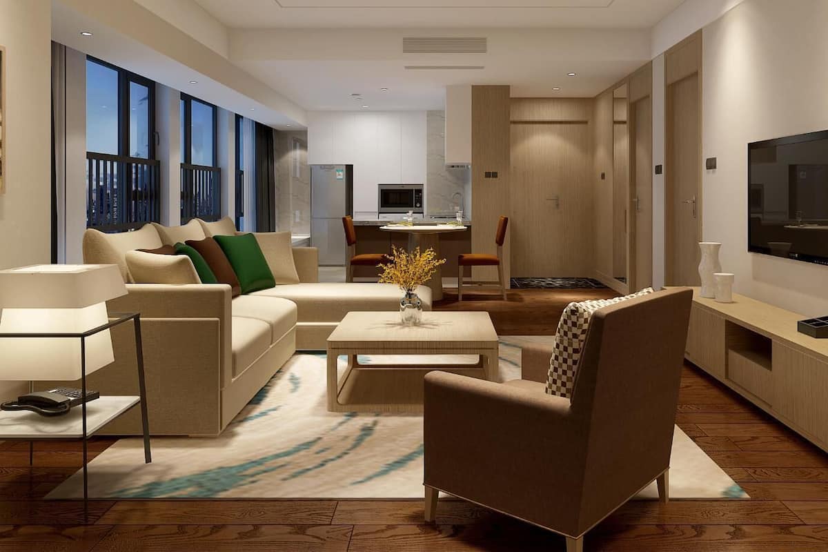 Una sala moderna con sofá, sillones, una mesa de centro y televisor. Cuenta con una zona de cocina con microondas y una mesa de comedor. La habitación tiene ventanas amplias y una estantería.