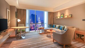 A modern hotel room with a large window offering a city view, a sofa, a small table, and a TV. - Hilton Garden Inn Ningbo (Ningbo)