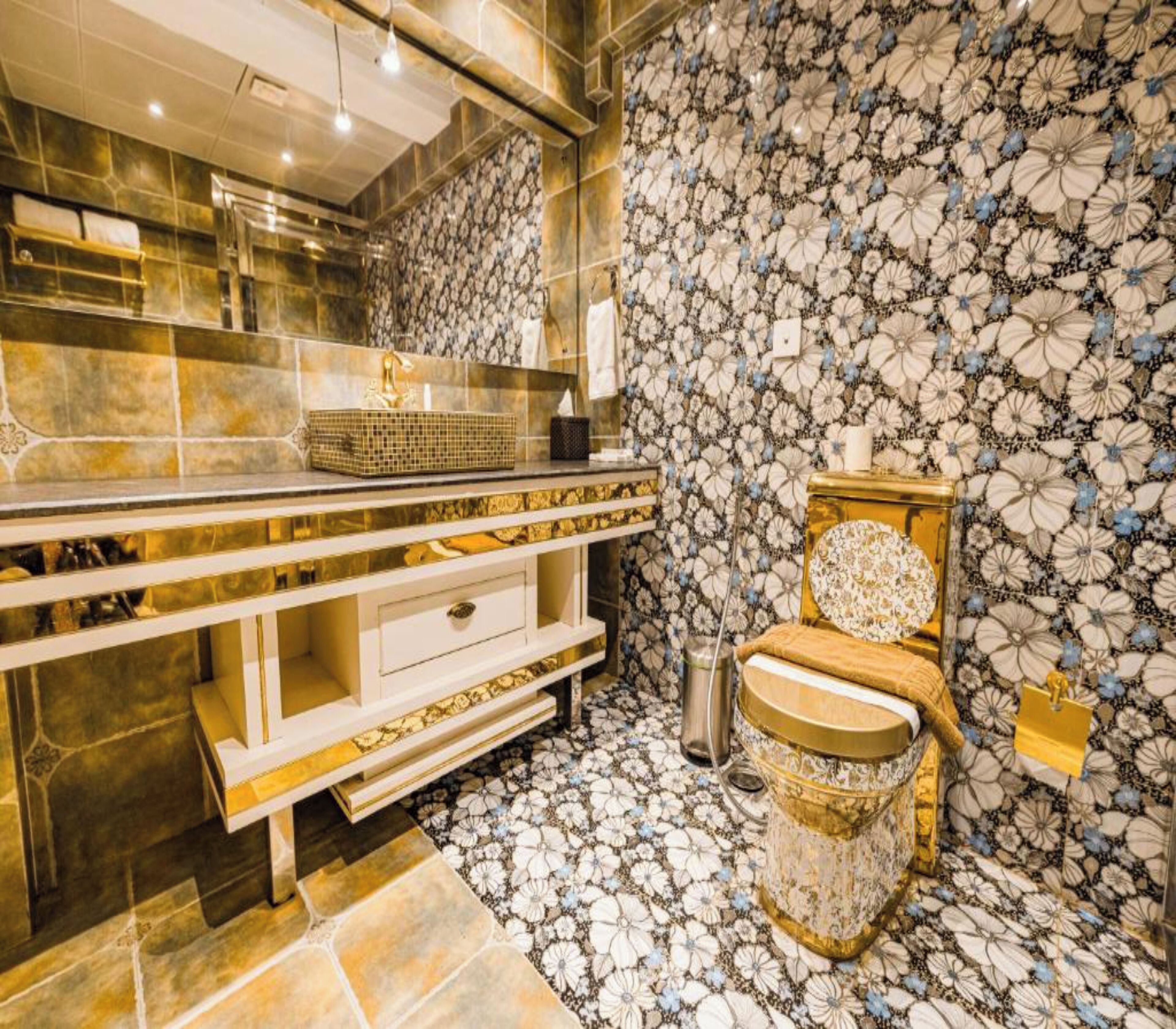 A bathroom with a marble vanity, a toilet with a decorative cover, and a patterned wall.