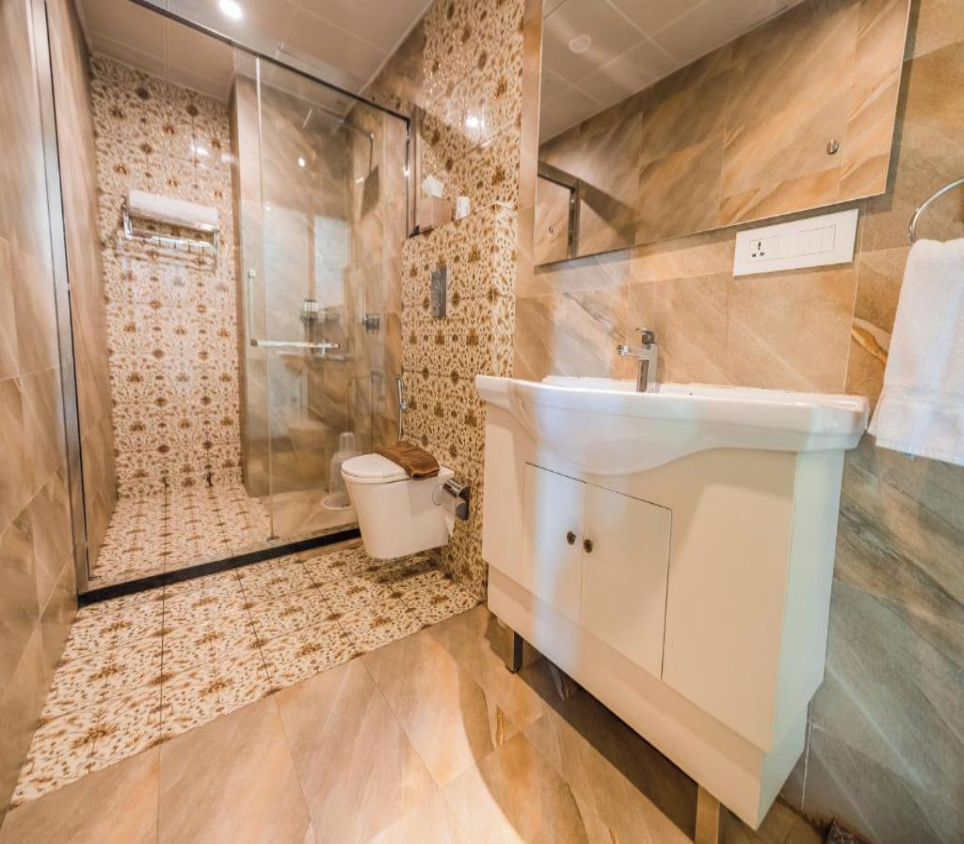 A modern bathroom with a glass shower enclosure, a white sink, and a marble-patterned wall.