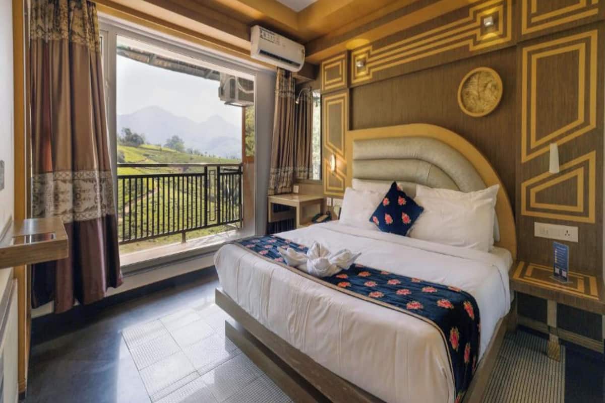 A hotel room with a large bed, a balcony with a view of mountains, and a modern design with geometric patterns on the walls.