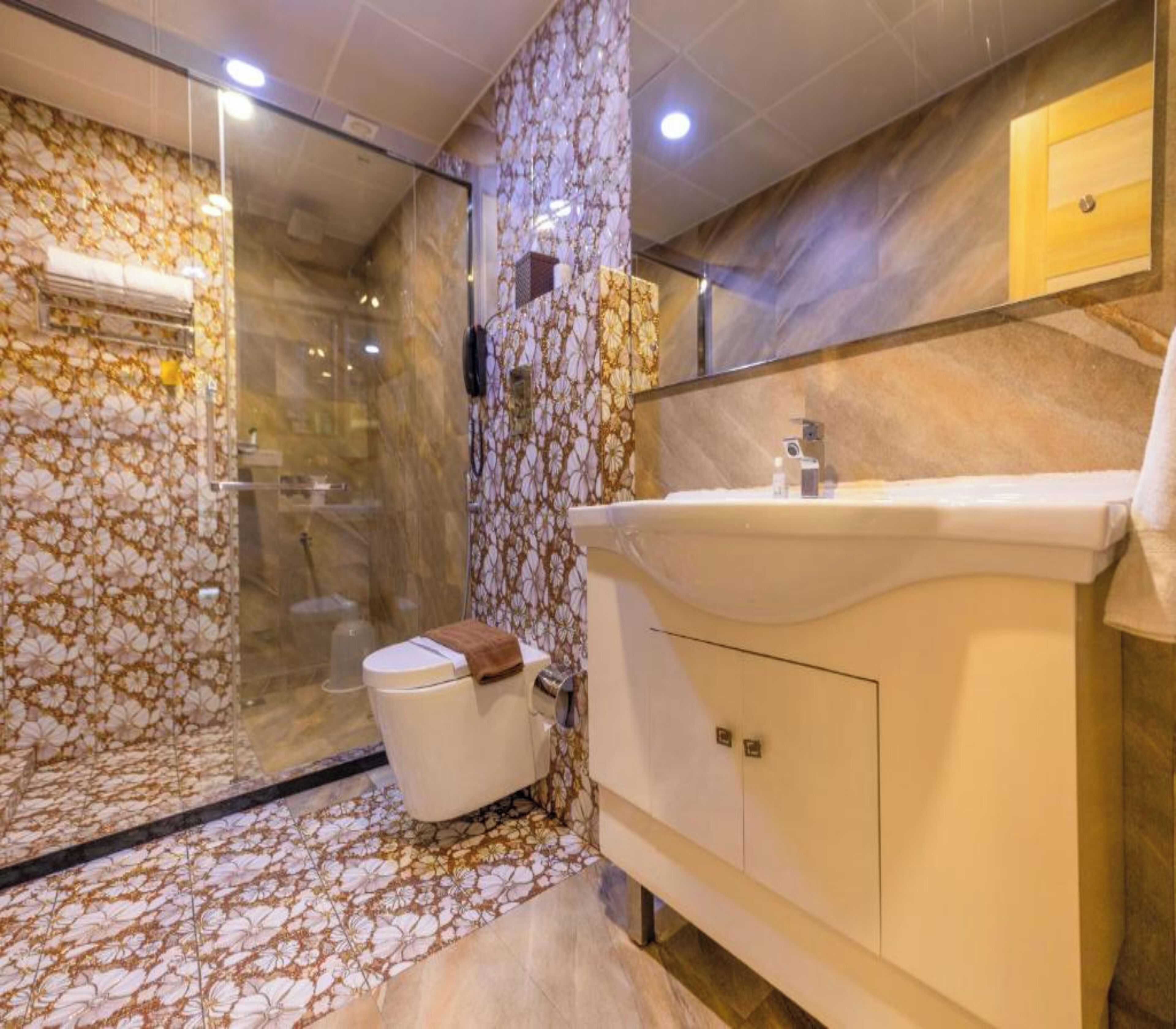 A bathroom with a glass shower enclosure, a toilet, and a sink with a mirror above it.