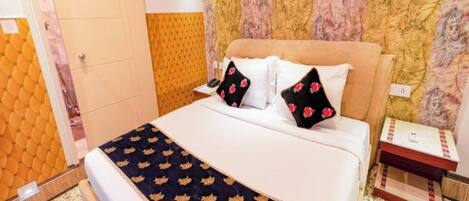 A hotel room with a bed, a nightstand, an air conditioning unit, and a patterned wall.