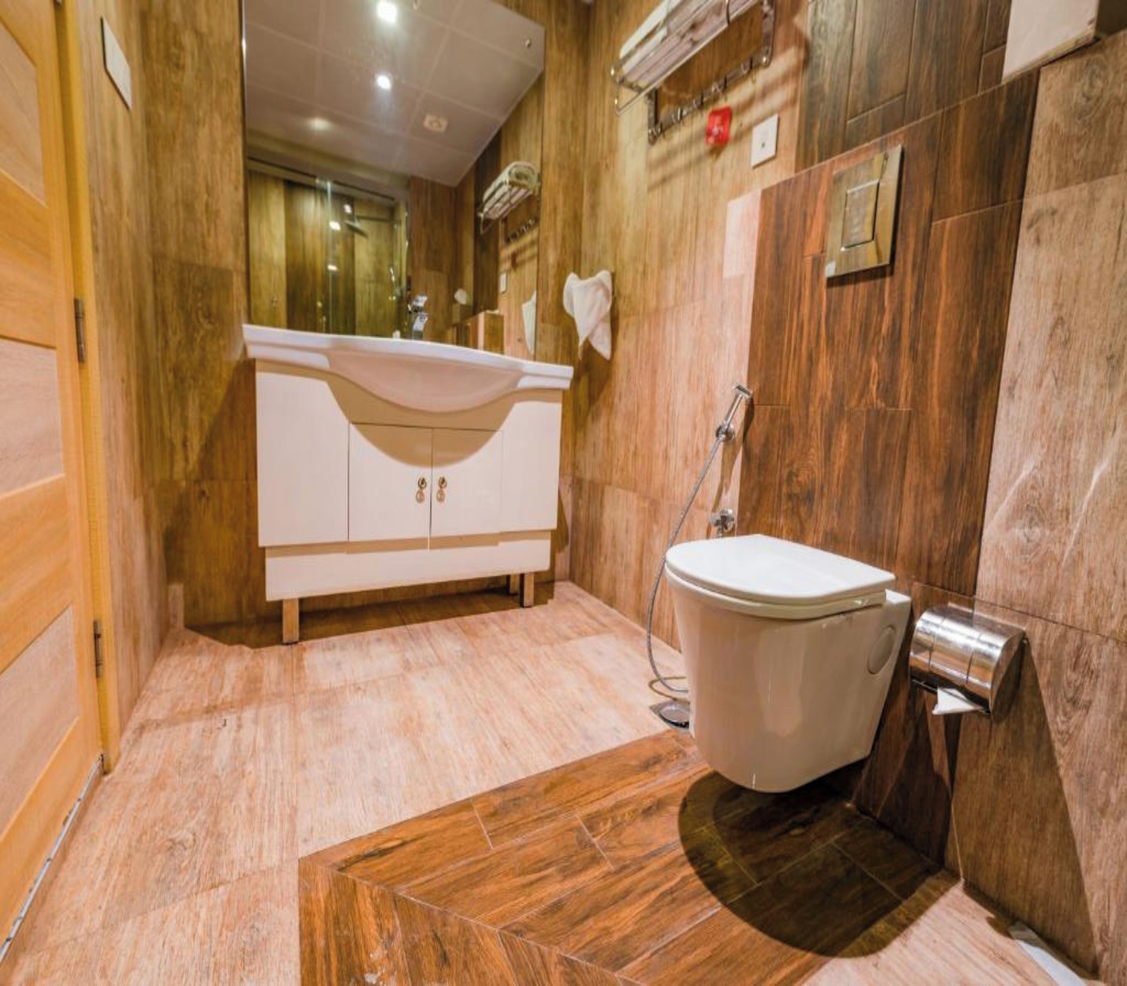 Un baño moderno con tocador de madera, inodoro y zona de ducha.