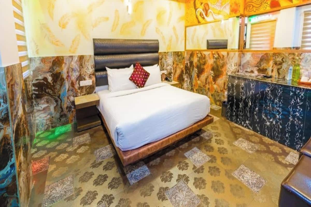 A hotel room with a large bed, marble walls, and a decorative mirror.