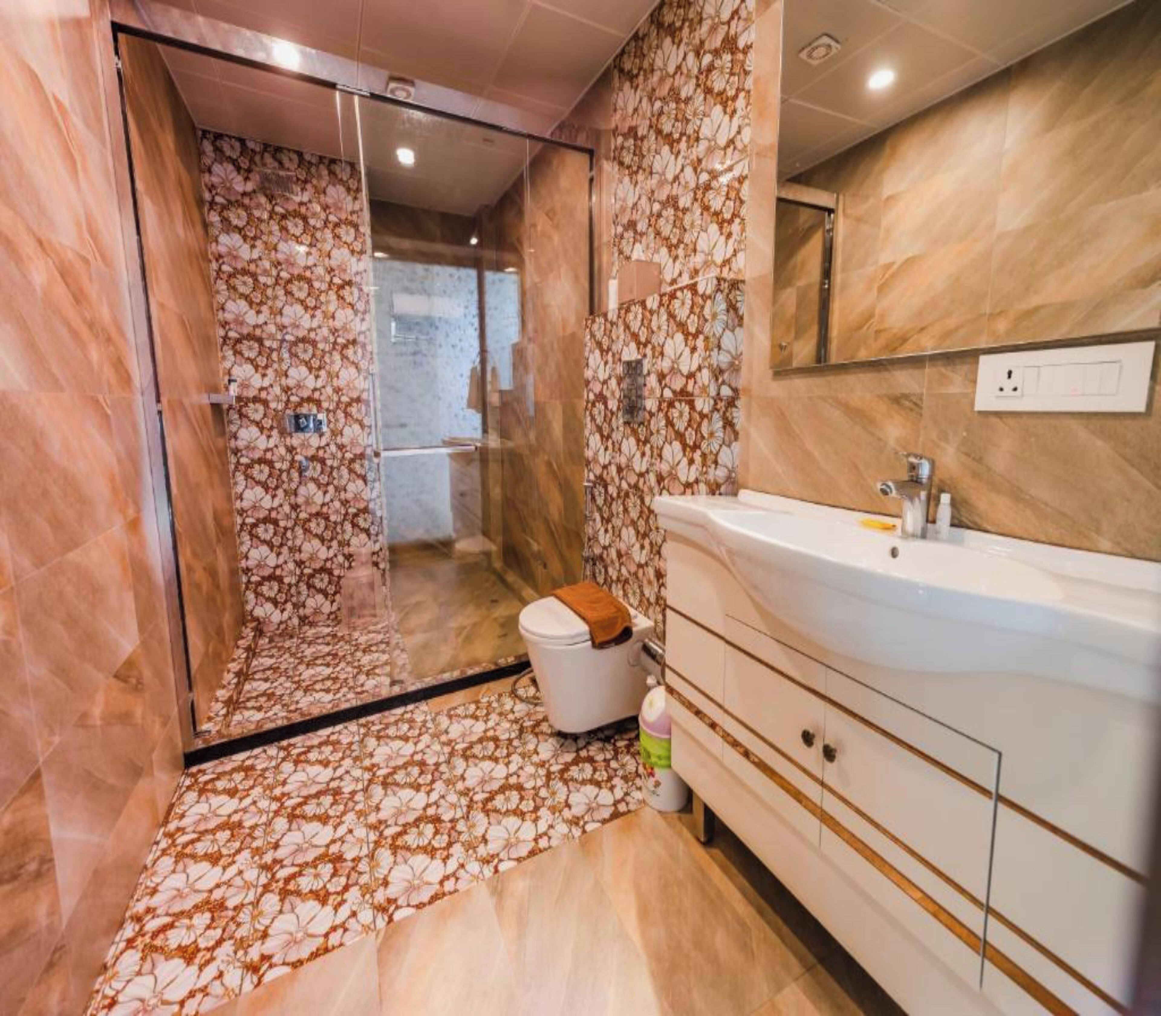 A modern bathroom with a glass shower enclosure, a white sink, and a marble floor.