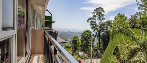 Ein Balkon mit Blick auf einen üppigen Garten und ferne Berge.