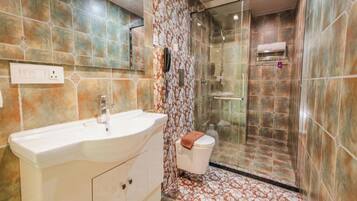 A bathroom with a large vanity, a shower enclosure, and patterned tiles.
