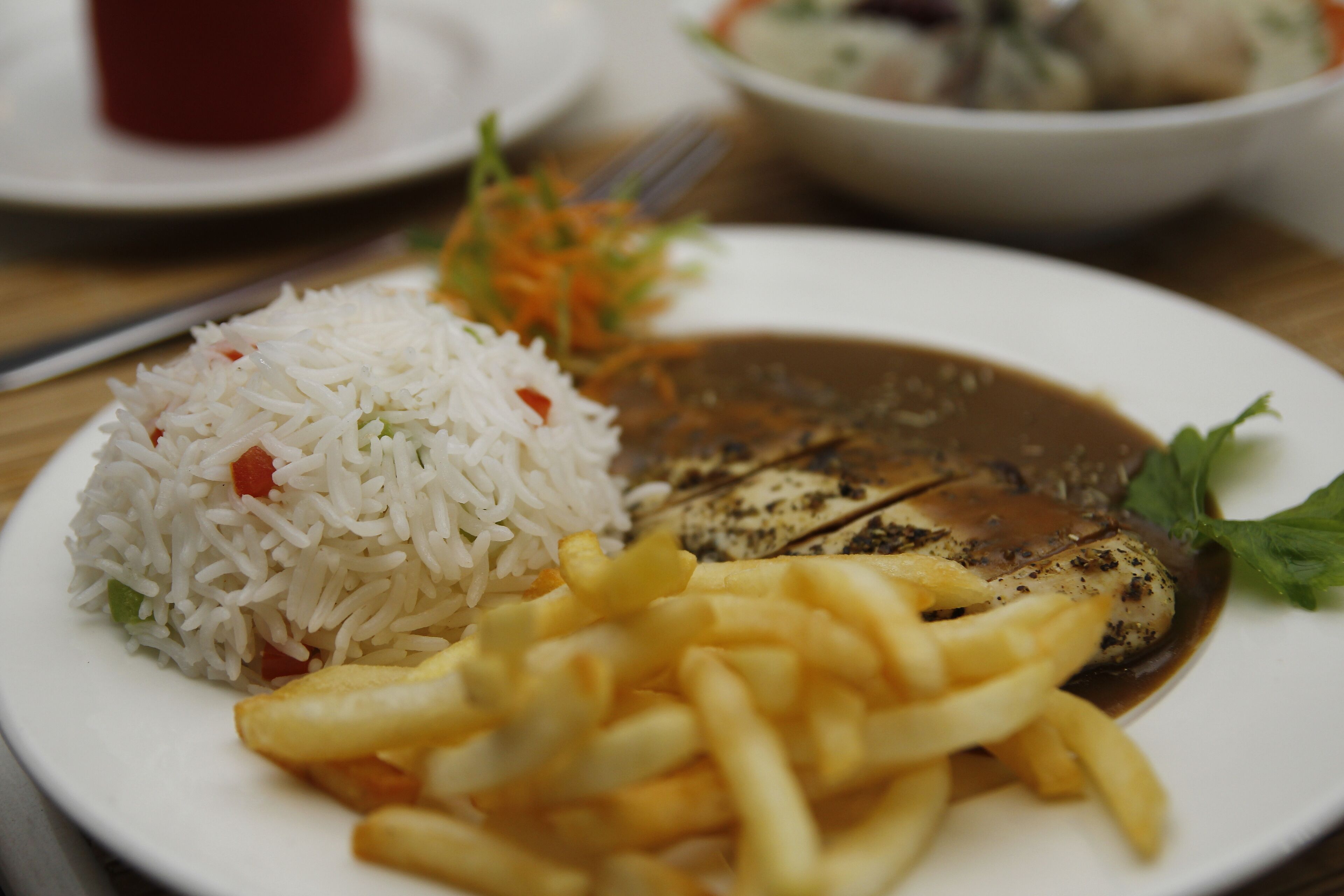 Un plato con arroz, papas fritas y un plato de pescado.