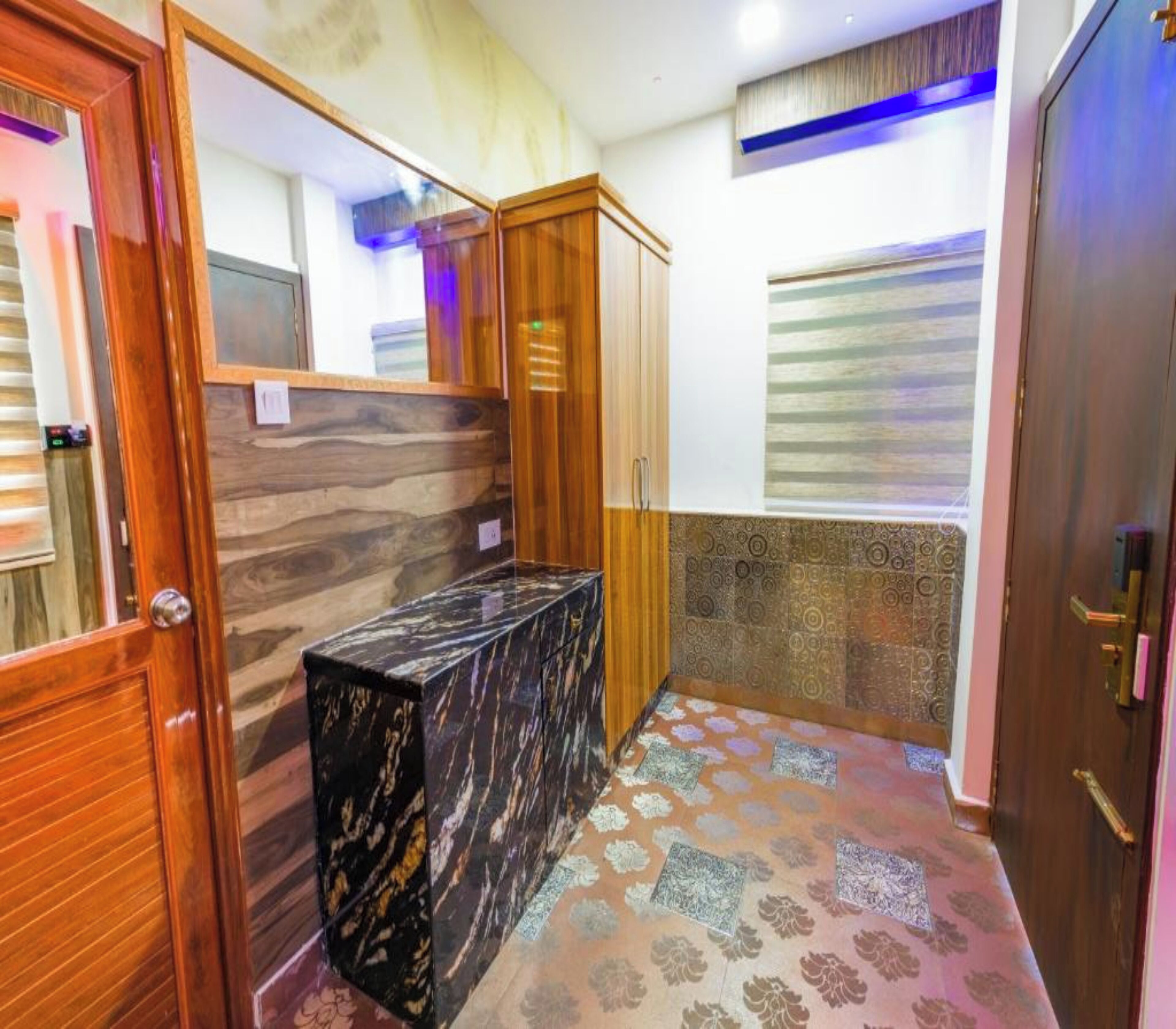 A bathroom with a marble vanity, wooden cabinets, patterned floor tiles, and a window with blinds.