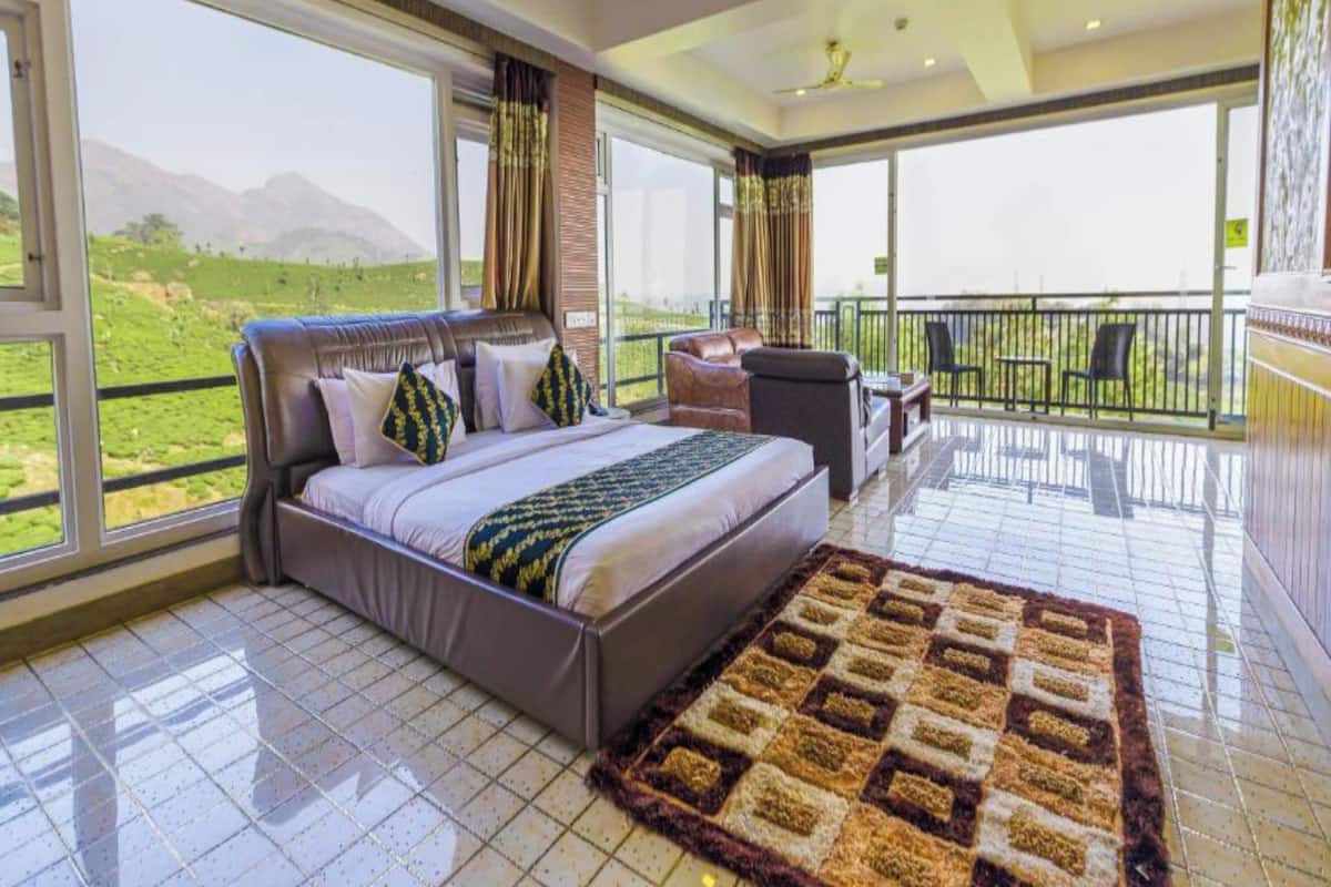 A spacious bedroom with a large bed, a balcony with a view of the countryside, and a modern design.