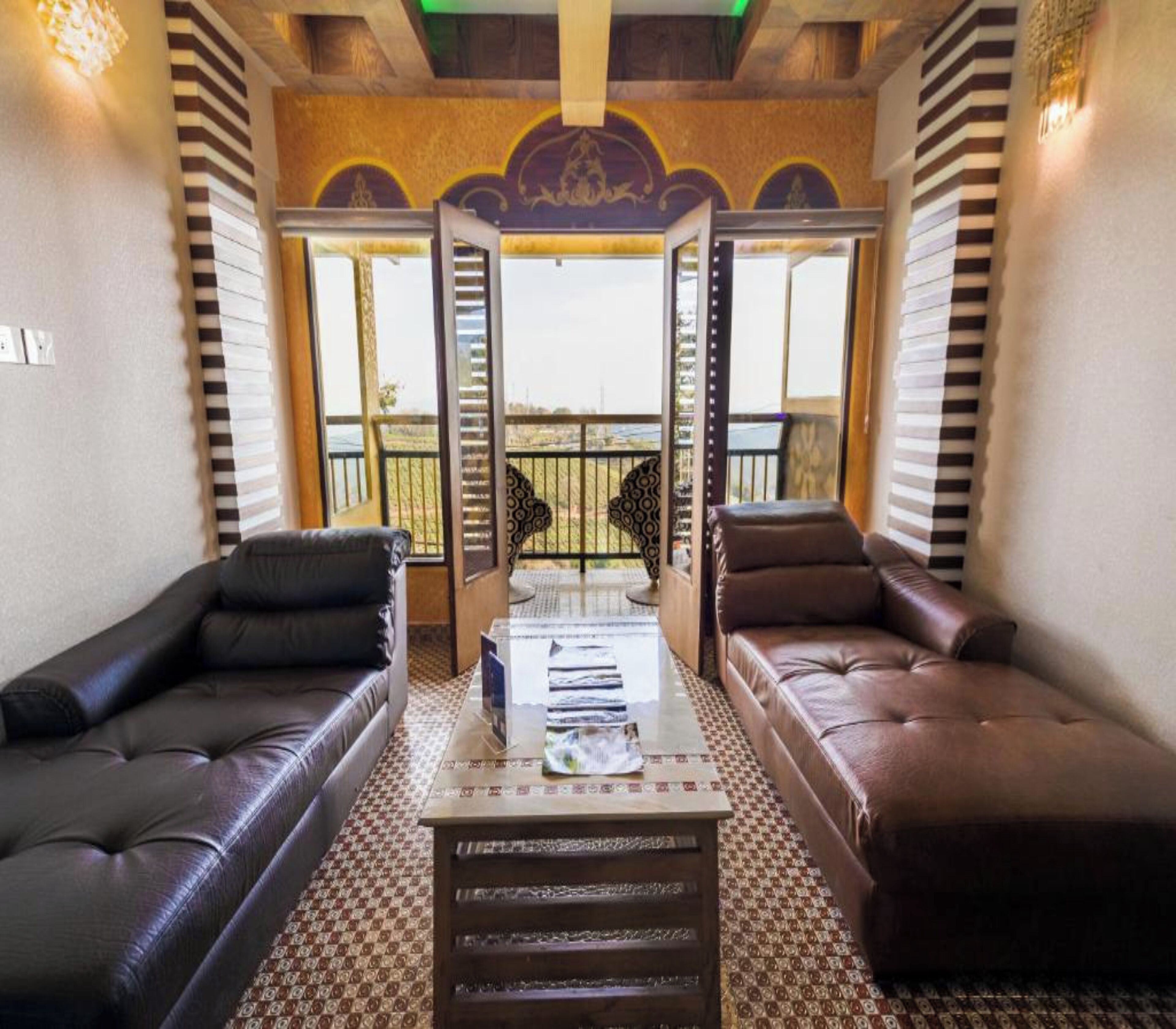 Ein Zimmer mit zwei Ledersofas, die eine Glastür gegenüberhaben, einem gemusterten Boden und Blick auf einen Balkon.