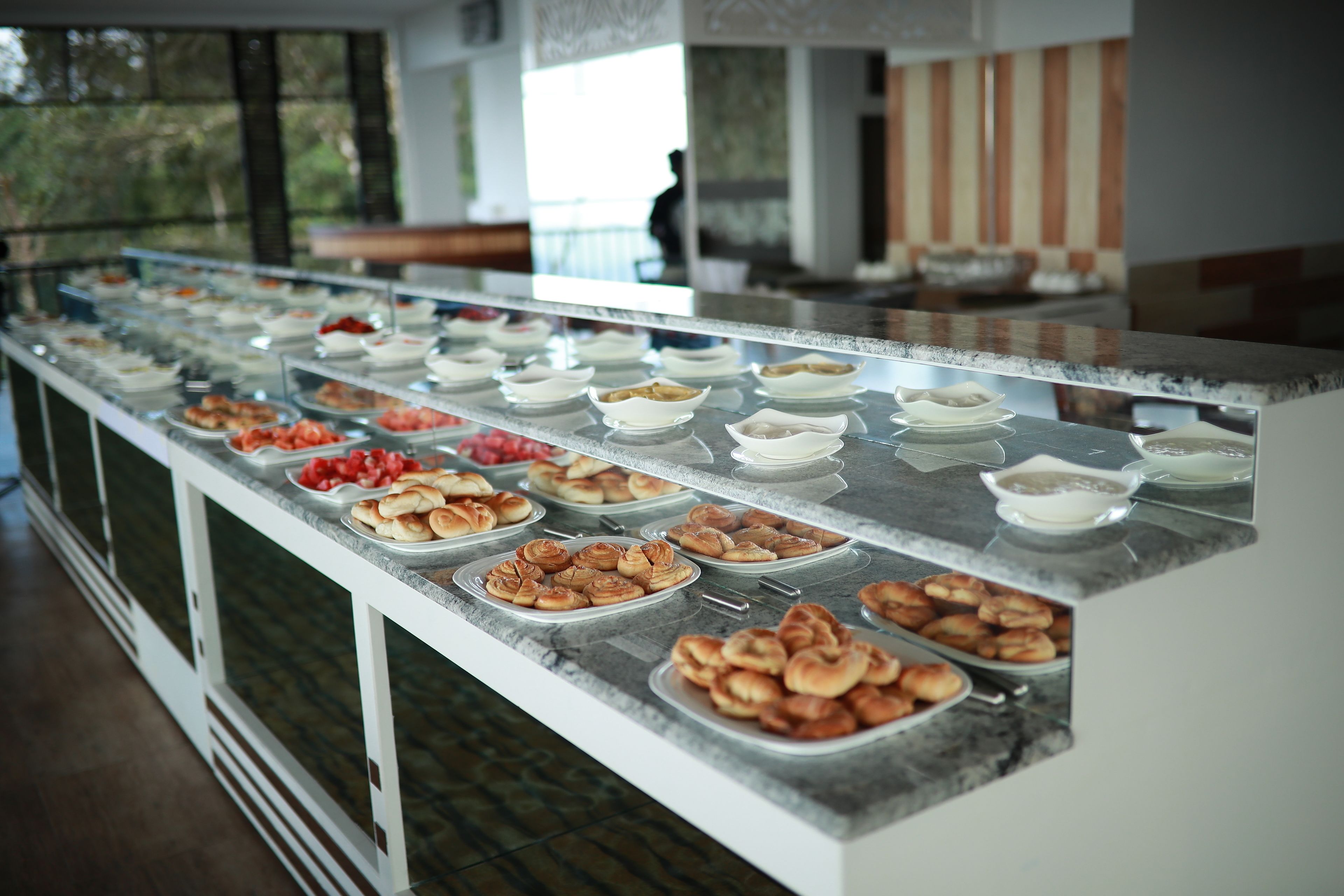 A buffet with various food items displayed on a marble counter.