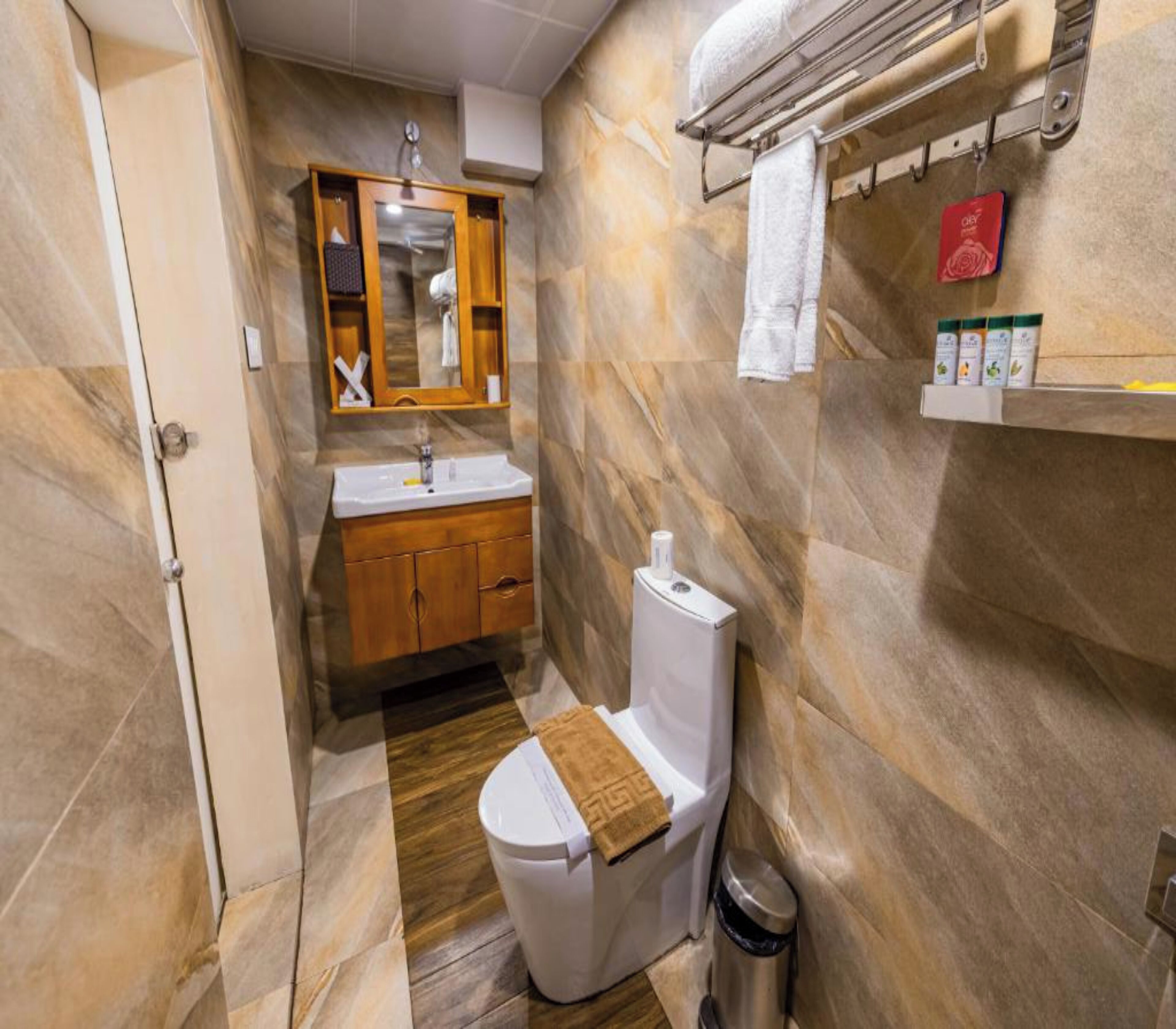 A bathroom with a wooden vanity, a toilet, a sink, and a mirror.