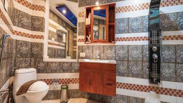 Un baño con baldosas estampadas, inodoro, lavamanos y espejo.