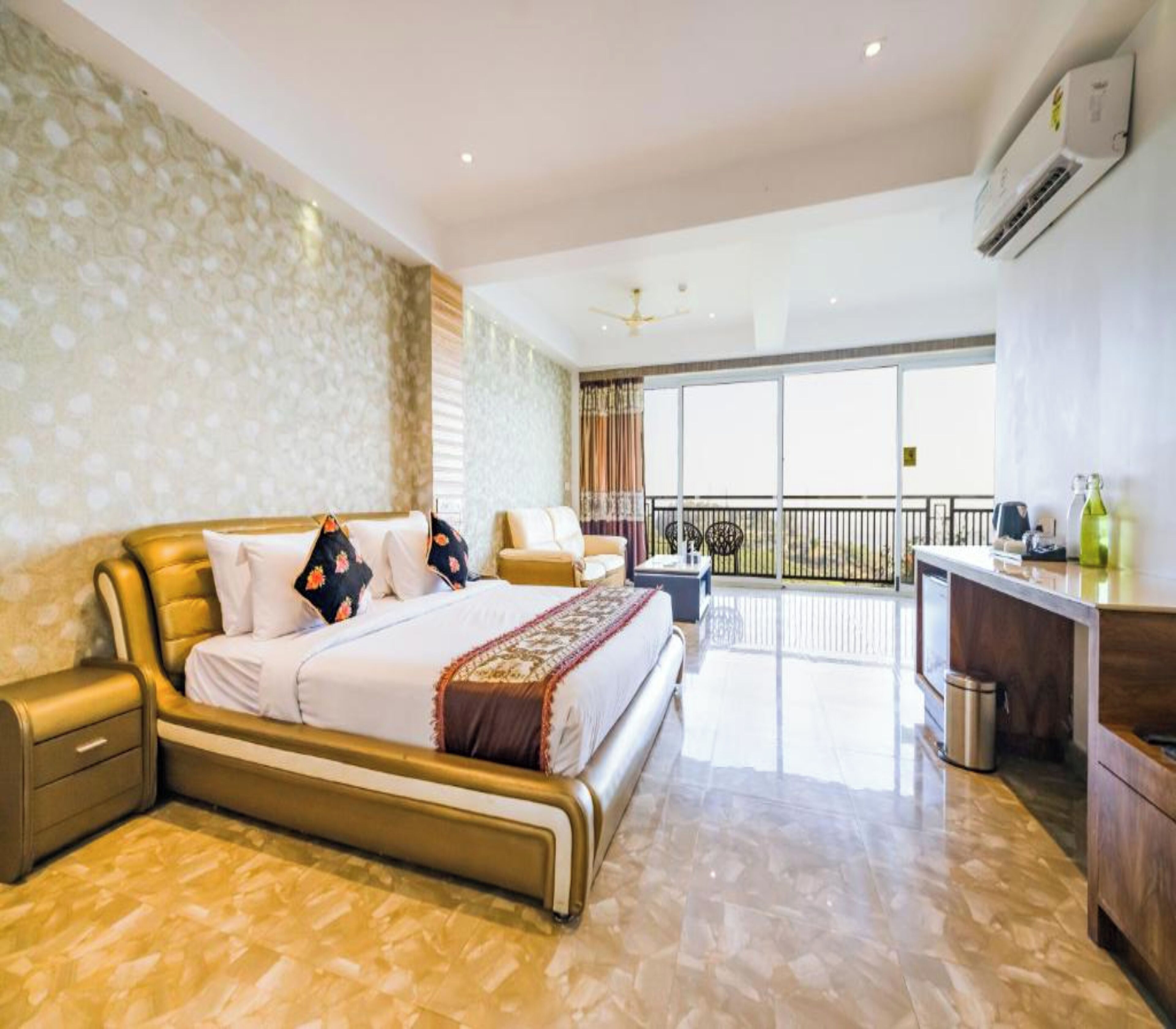 Ruime slaapkamer met een groot bed, een balkon en een werkplek.