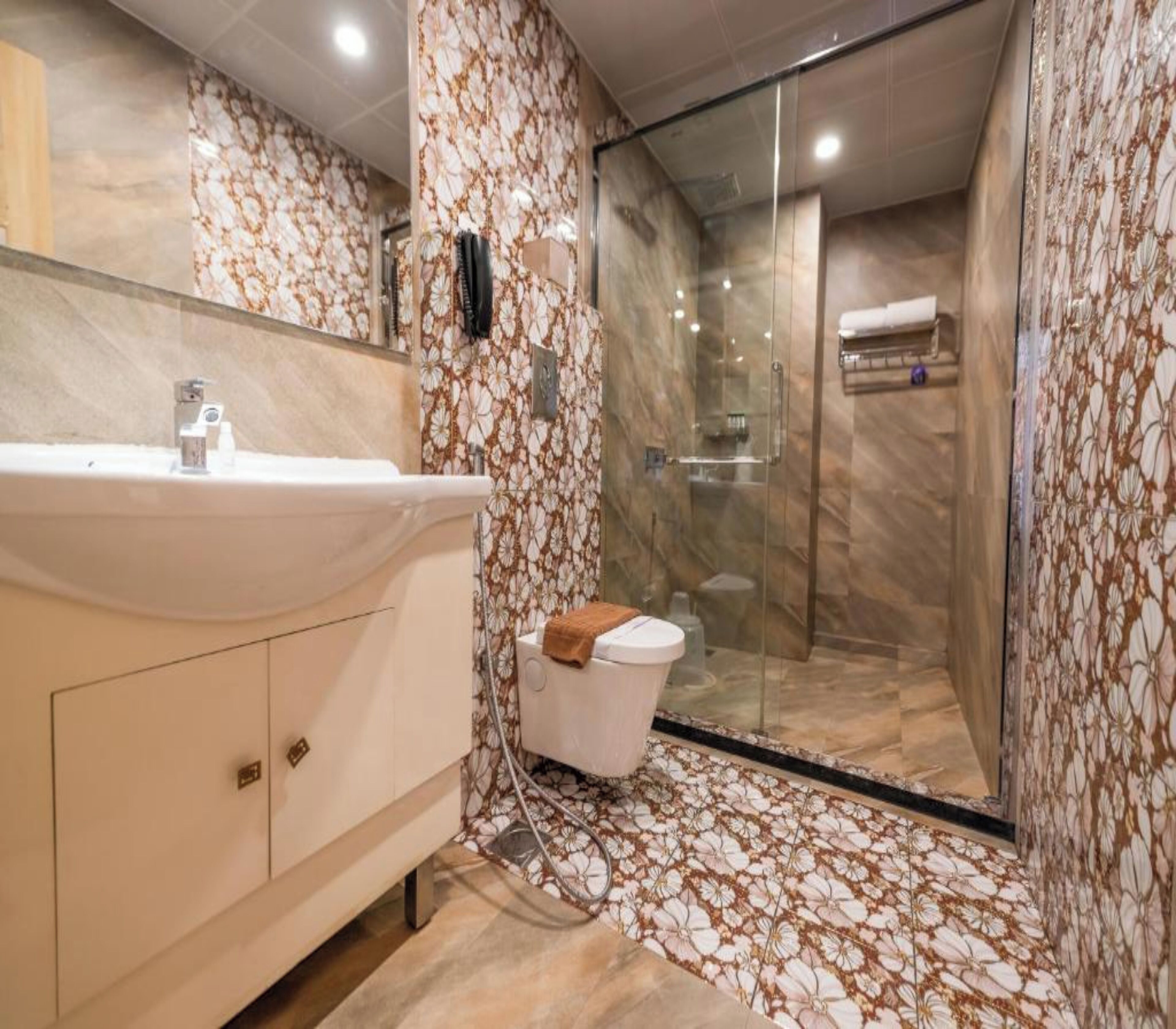 Ein Badezimmer mit Marmorwaschbecken, einer Duschkabine aus Glas und einer Toilette.