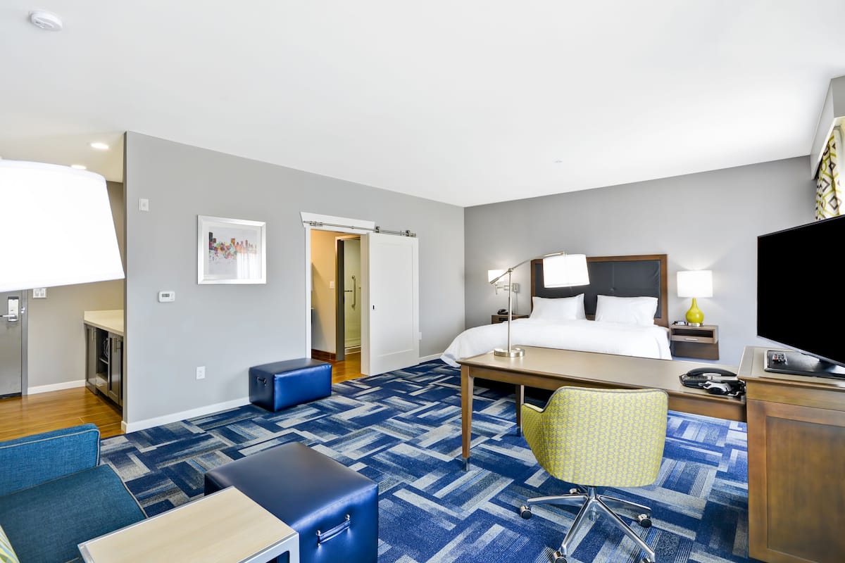 A hotel room with a bed, desk, chair, and a television.